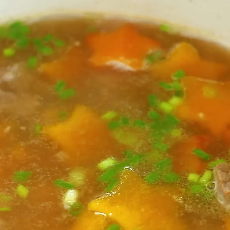 Múc canh ra tô và chuẩn bị hành lá để trang trí món ăn