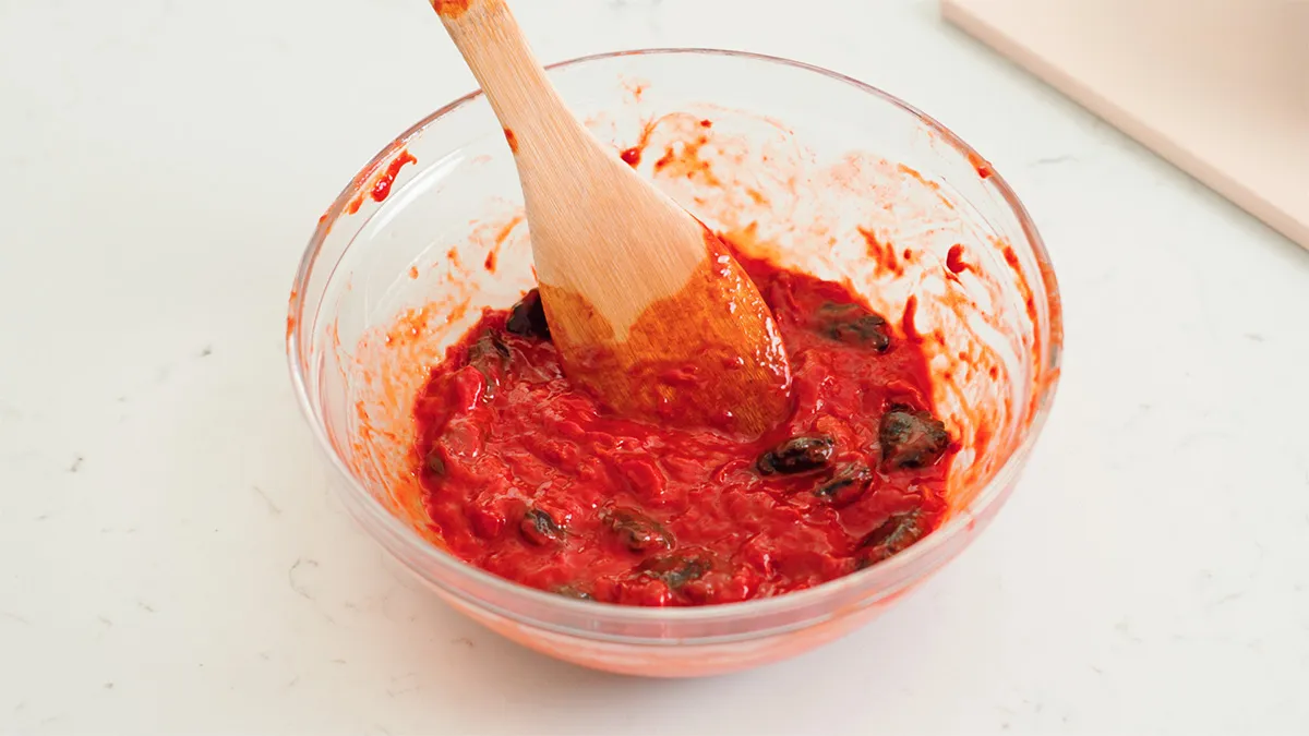 Tách lấy phần thịt gấc đỏ tươi để chuẩn bị nấu xôi