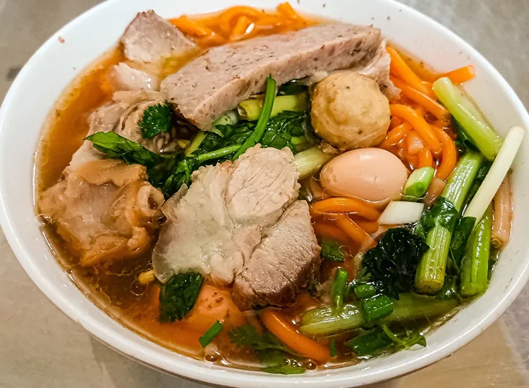 Canh bún đỏ hoàn chỉnh với sợi bún đỏ tươi, nhân tôm thịt và rau xanh