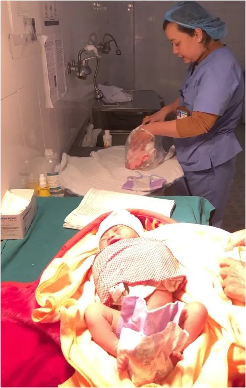 Bé sơ sinh đang được tắm trong chậu nước ấm an toàn