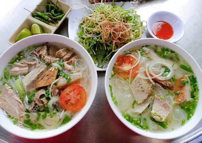 Bàn ăn với bát bún cá Phong Thủy, quẩy nóng và rau sống tươi ngon