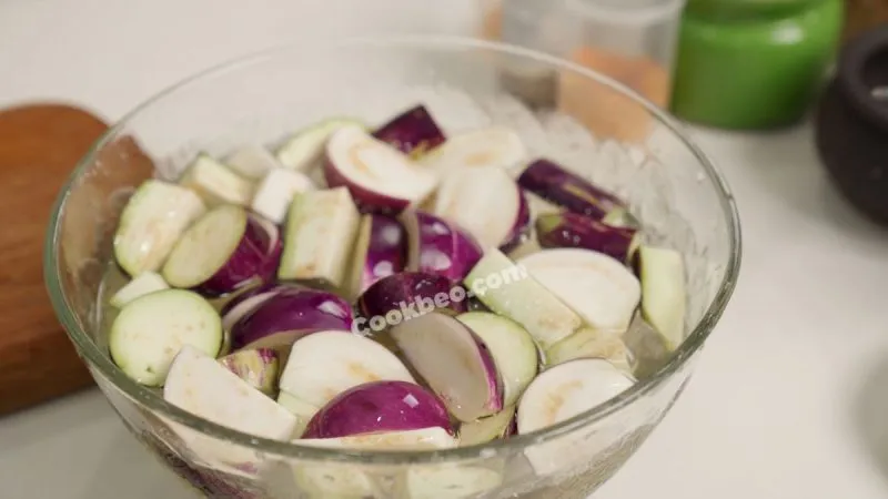 Cà tím thái miếng đang ngâm nước muối loãng, bí quyết sơ chế cà cho món ếch xào cà không bị thâm