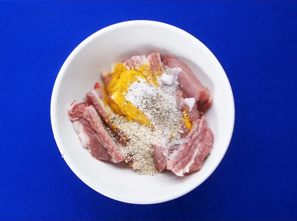 Ướp sườn non heo với gia vị và bột nghệ giúp món lagu có màu sắc hấp dẫn