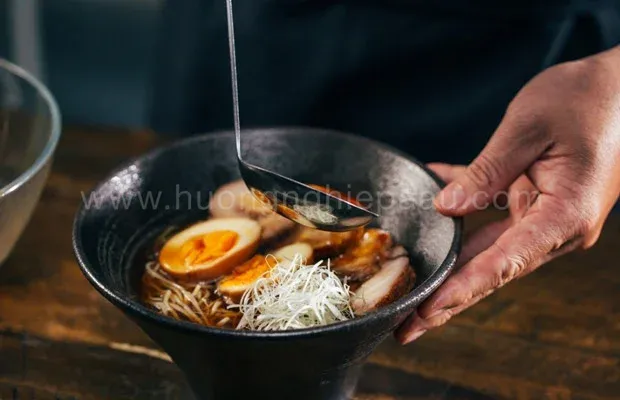 Công đoạn chan nước dùng vào tô mì đã được sắp xếp nguyên liệu