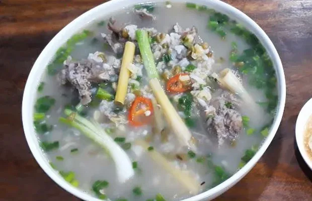 Cháo thịt dê trong tô với rau thơm