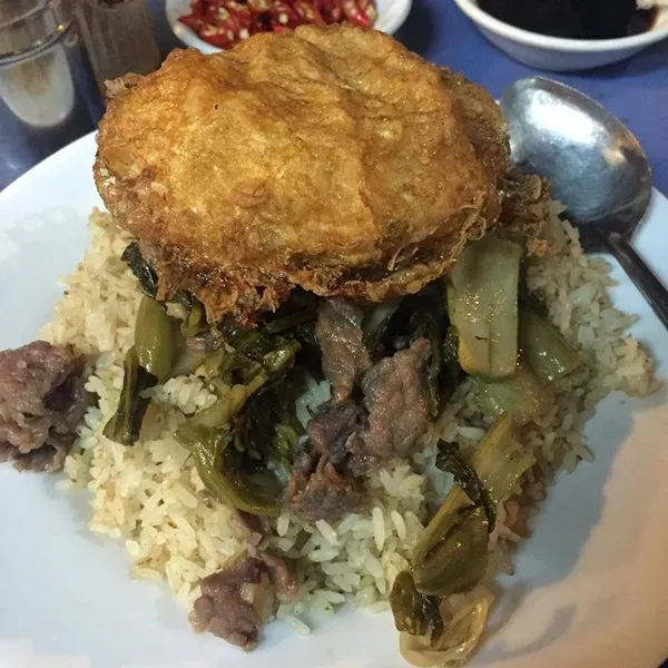 Đĩa cơm rang trứng vàng ươm, kèm theo dưa bò và một bát nước chấm đặc trưng