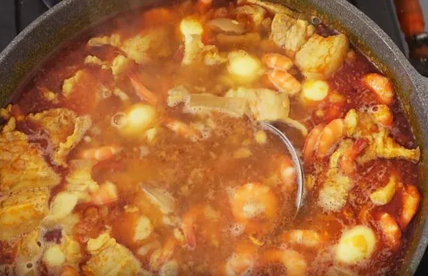 Nước nhân mì quảng đang sôi trên bếp với màu vàng đặc trưng của nghệ và dầu điều