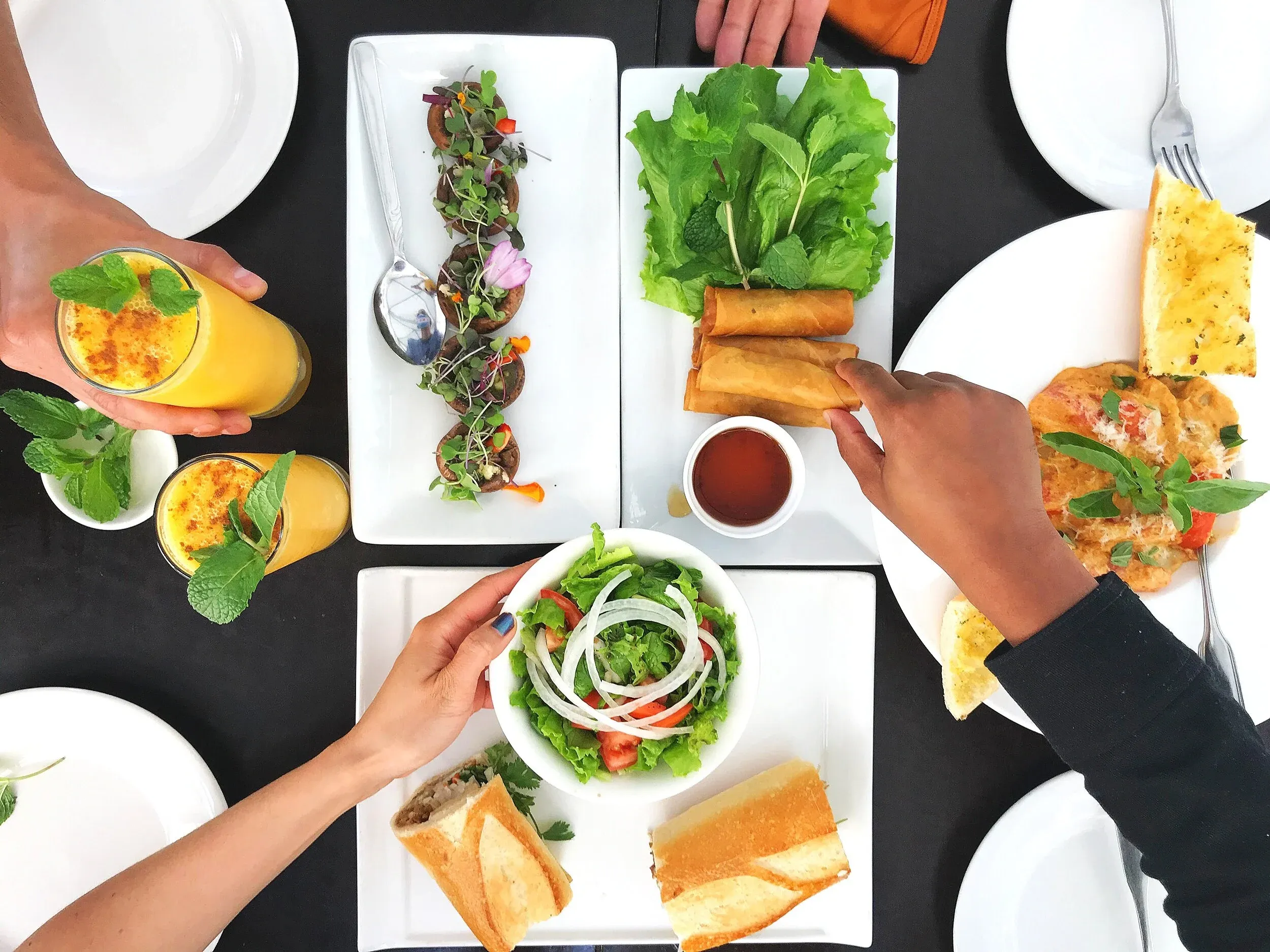 Bàn tiệc đa dạng tại nhà hàng âu lạc đà lạt với bánh mì, gỏi cuốn, nấm nhồi và các loại sinh tố tươi mát