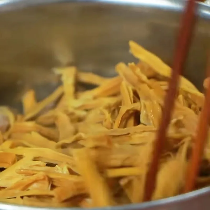 Thêm nước dừa và măng khô vào nồi để bắt đầu quá trình hầm chậm