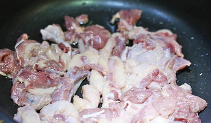 Thịt vịt đang được xào săn trên chảo với hành và gia vị