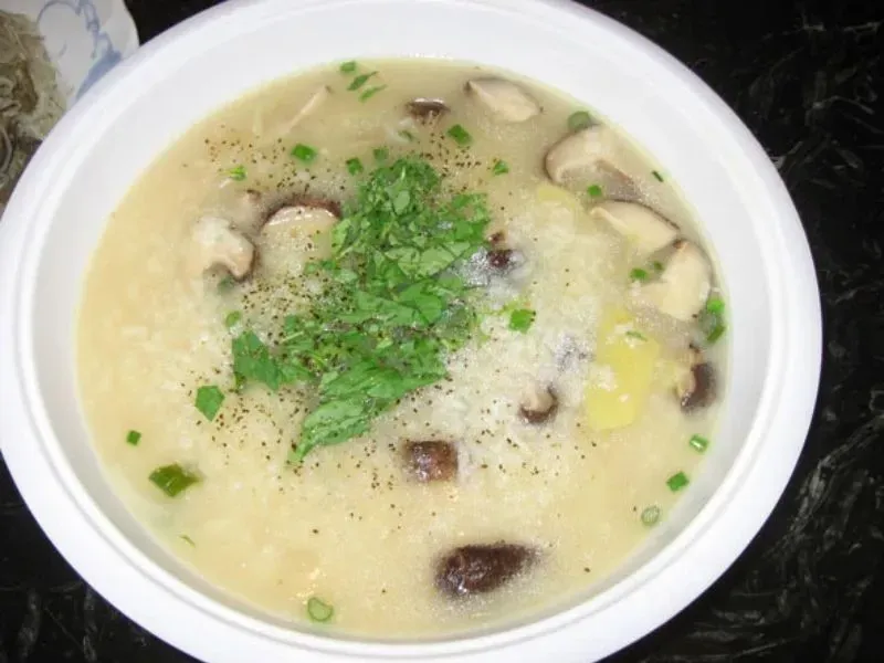 Cháo gà nấm rơm với nấm cắt nhỏ và hành lá xanh tươi