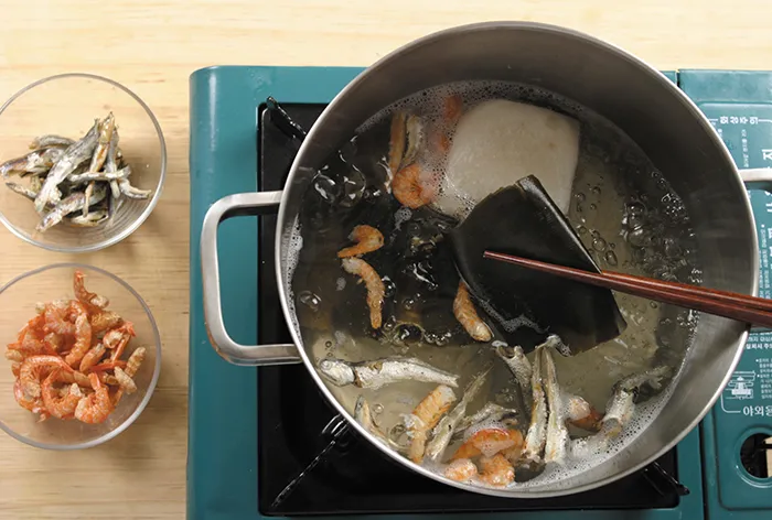 Nước dùng mì được nấu bằng cách cho củ cải, cá cơm khô, tôm khô vào nồi nước, đun sôi lửa to 10 phút, sau đó hạ lửa vừa thêm 10 phút, cuối cùng cho rong biển và tắt bếp