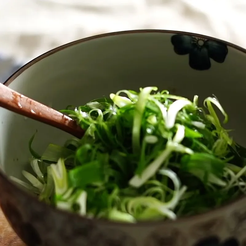 Công đoạn trộn hành lá với sốt chua cay để làm món ăn kèm đúng điệu