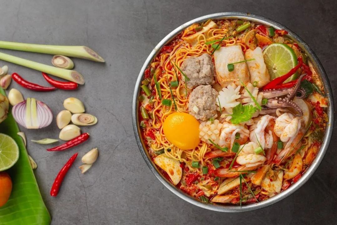 Nồi lẩu Thái chua cay với nước dùng trong vắt, xương ống hầm ngọt, tôm tươi và rau xanh