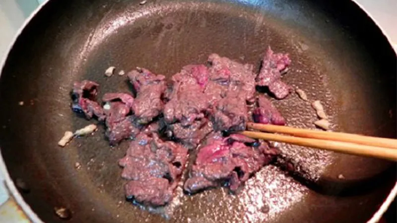 Thịt bò đang được xào trên chảo với lửa lớn