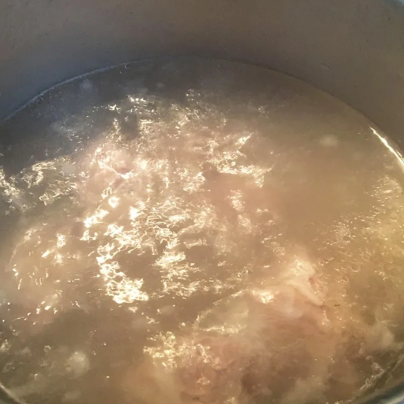 Xương heo đang được ninh trong nồi nước dùng trong vắt đầy hấp dẫn