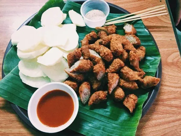 Những chiếc nem chua rán vàng giòn, đặt trên đĩa cùng dưa chuột thái lát và nước chấm tương ớt