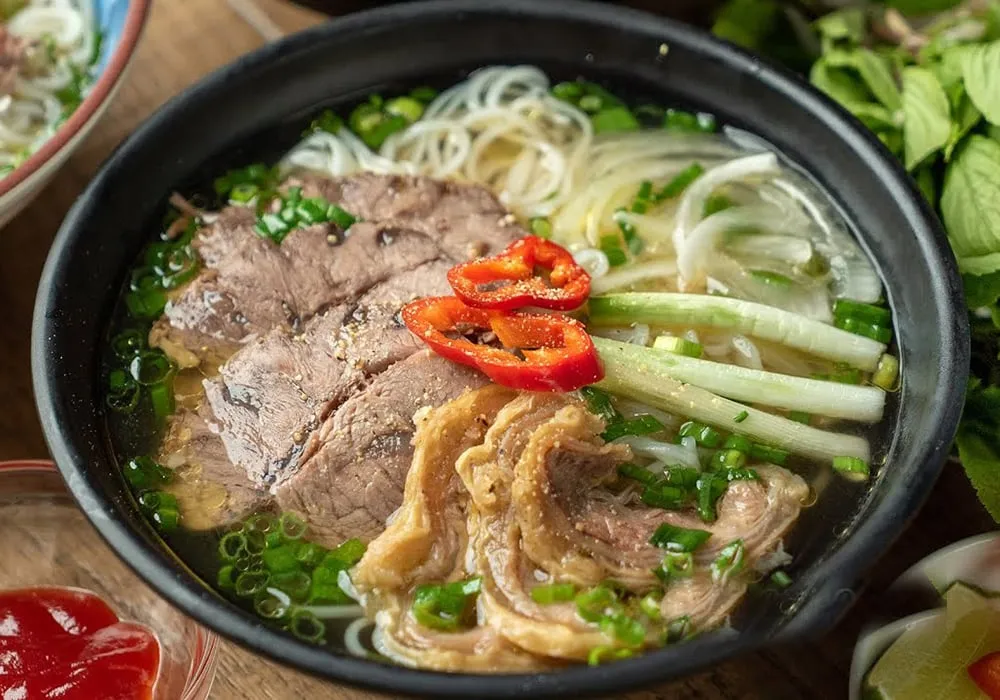 Phở nạm bò với nước dùng trong vắt, bánh phở mềm và rau thơm tươi