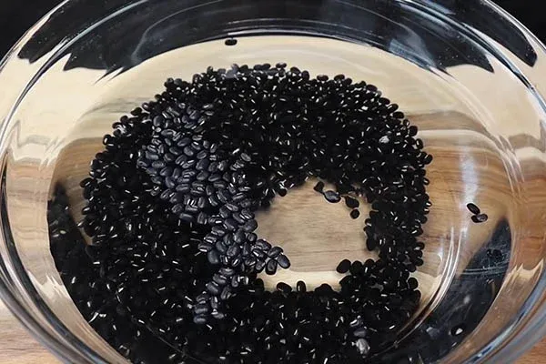 Rửa sạch đậu với nước trước khi rang là bước quan trọng trong cách nấu nước đậu đen rang