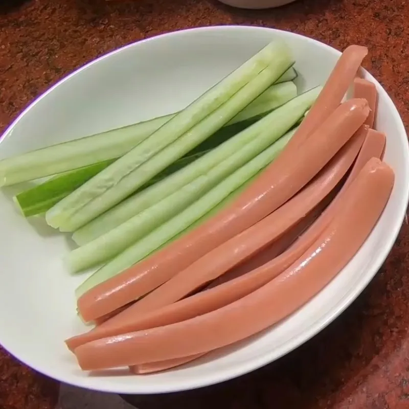 Thái xúc xích và dưa leo thành các thanh dài chuẩn bị cho khâu cuộn nhân