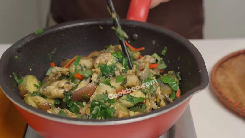 Thêm lá lốt và ớt vào món ếch xào cà đang hoàn thành, tăng thêm hương vị và màu sắc