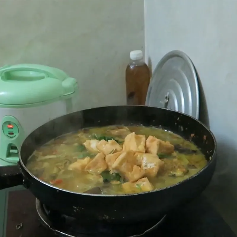 Rau thơm và hành lá được thêm vào nồi cá lăng om chuối đậu trước khi hoàn thành