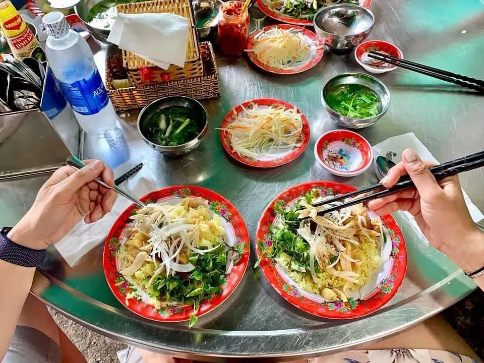 Đĩa cơm gà Bà Buội với thịt gà xé sợi, rau thơm và nước sốt đặc trưng