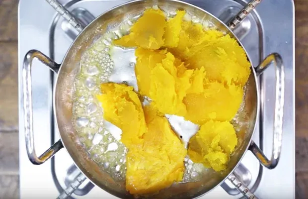 Quá trình cho bí đỏ vào nồi xào sơ qua rồi nghiền nát cho nhuyễn